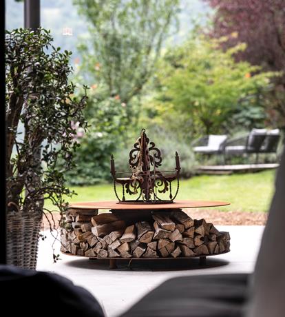 Area relax nel giardino dello Sport Hotel Panorama con tavolo in legno e vista sul verde delle Dolomiti.