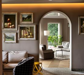 Salotto elegante dello Sport Hotel Panorama con parete decorata da quadri, arco architettonico e area lounge luminosa in stile alpino contemporaneo.