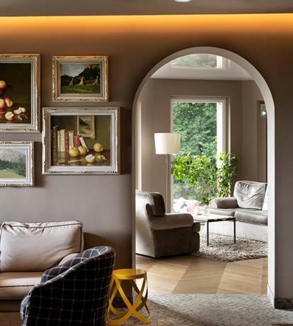 Salotto elegante dello Sport Hotel Panorama con parete decorata da quadri, arco architettonico e area lounge luminosa in stile alpino contemporaneo.