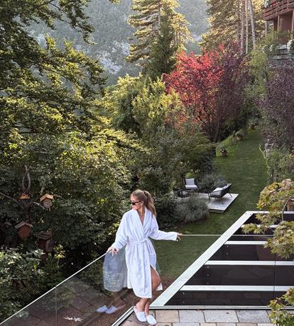 Ospite in accappatoio sulla terrazza panoramica immersa nel verde, relax e natura allo Sport Hotel Panorama a Fai della Paganella.