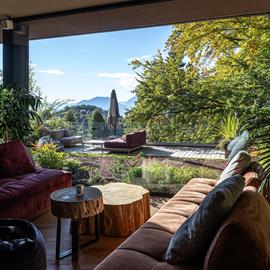 Lounge panoramica  in Paganella, con grandi vetrate e vista sulle Dolomiti. salotti moderni in palette ideali per set fotografici.