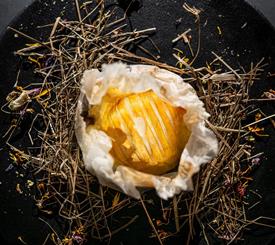 piatto nero gourmet con fieno e pietanze montane