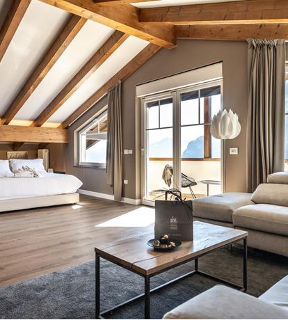 Travi in legno, luce naturale e vista sulle Dolomiti: una suite spaziosa dove vivere il tuo soggiorno in totale comfort.